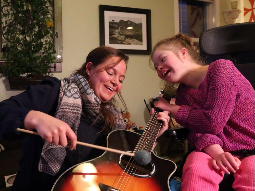 Emily Pitchers, 16, plucks the strings on a guitar with JB Music therapist Catherine Mitchell during a weekly session at the teenager’s family home. Christina Ryan, Calgary Herald.