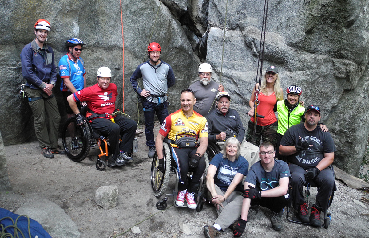 The group prepares to climb Chapel Wall with Mark Wellman’s adaptive climbing system, which supports the climber via a seat and chest harness. Climbers ascend with a pull-up bar using pulley systems that require them to lift a fraction of their weight.