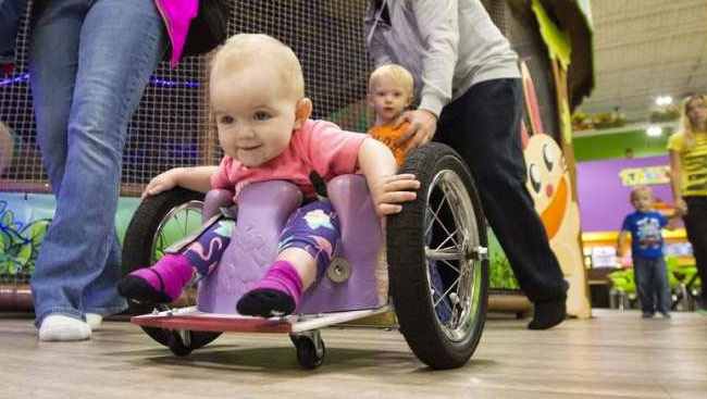 Evelyn Moore isn't the fastest kid on the racetrack, but she's by far the tiniest. At 13-months old, the paralyzed toddler skilfully wheels her homemade wheelchair around the simulated track at Treehouse, an indoor playground in northeast Edmonton that she often visits with her mom. Jason Franson/The Canadian Press